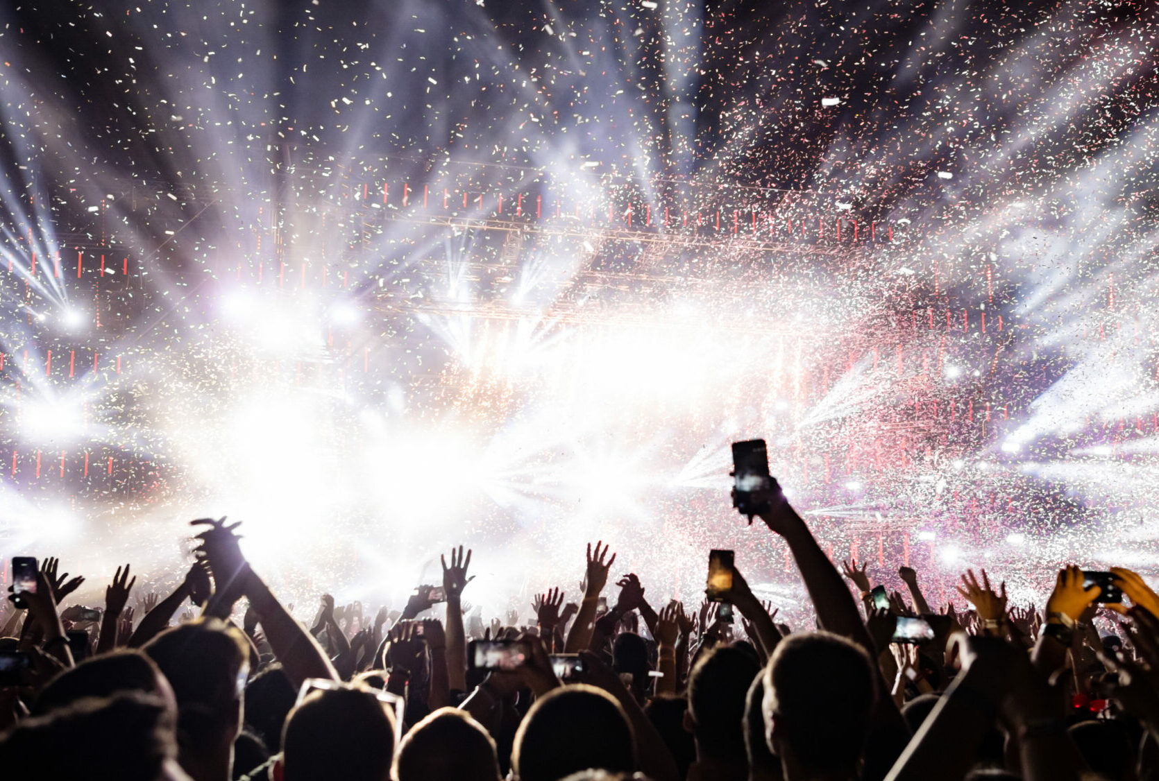 Excited audience watching confetti fireworks and having fun on music festival at night. Copy space.